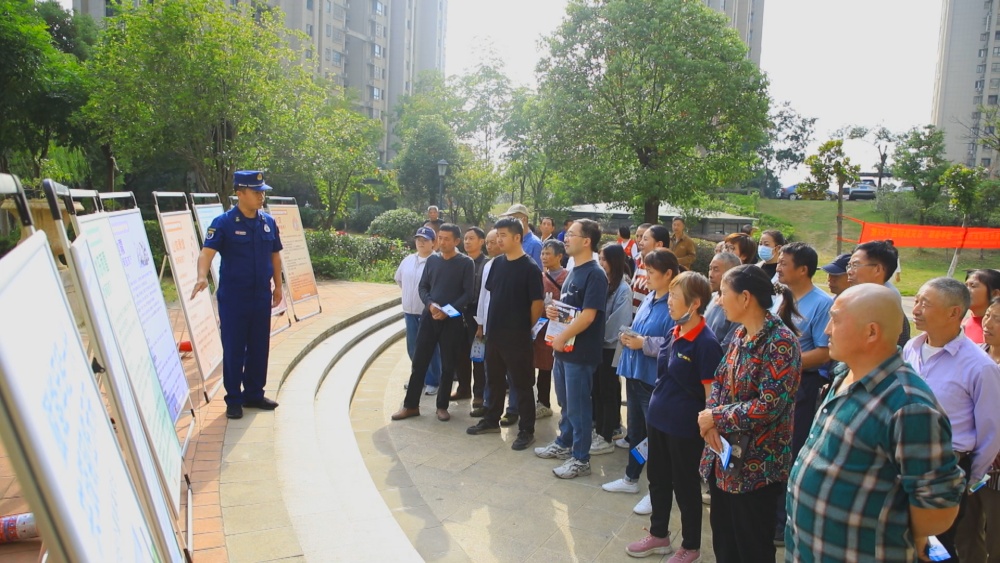 圖為消防員正在結合展板為小區居民講解防災減災自救知識.jpg